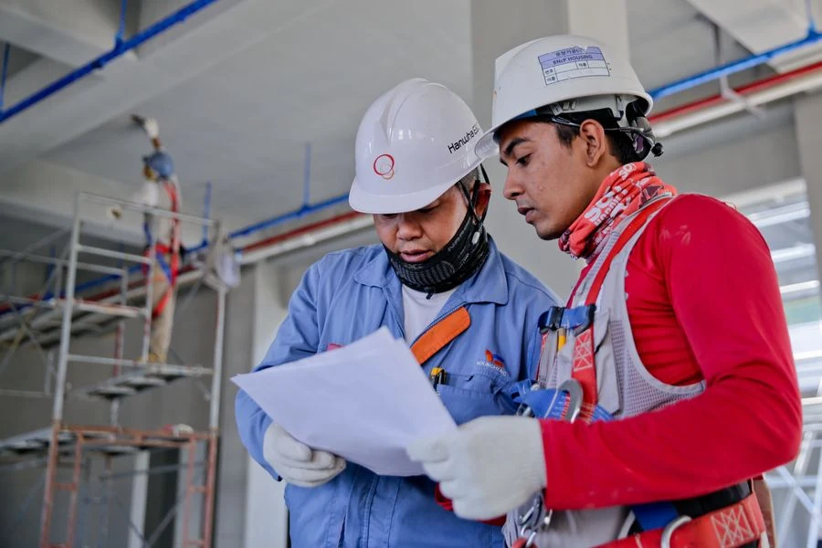 Two site workers reviewing drawings on a construction site